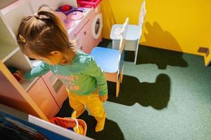 baby meisje spelen Bij binnen- kinderen keuken speelplaats. foto