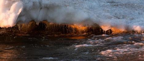 Baltisch zee kust met steentjes en ijs Bij zonsondergang foto