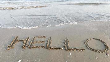 een woord Hallo door handschrift Aan de strand en zee Golf foto