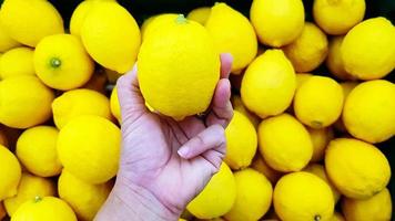 dichtbij omhoog hand- van persoon Holding citroen met kopiëren ruimte. selectie en keuze voor kopen het beste voedsel, groente of fruit Bij markt of supermarkt. foto