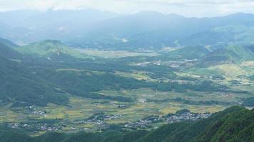 de oogsten geel rijst- veld- visie gelegen in de vallei tussen de bergen met de bewolkt lucht net zo achtergrond foto