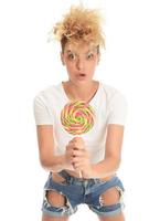 blond vrouw likken zoet snoep. vrouw model- aan het eten heerlijk banketbakkerij lolly met verrast uitdrukking. foto