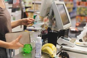 vrouw klant betalen via credit kaart gebruik makend van nfc technologie in boodschappen doen winkelcentrum. foto