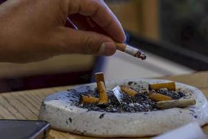 jong Mens roken Aan een houten tafel, asbakje met meerdere gebruikt sigaren, Mexico foto