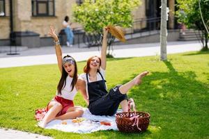 twee Dames hebben picknick samen, zittend Aan de plaid foto