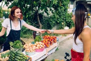 verkoper vrouw aanbiedingen vers en biologisch groenten boeren markt. foto
