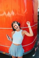 jong vrouw luisteren muziek- met draadloze hoofdtelefoons in de straat foto