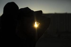 silhouet van Mens Bij zonsondergang. vent in pet en straal van licht. straat fotografie. foto