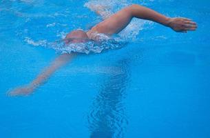 vrije stijl zwemmen in de zwemmen zwembad. jong Mens zwemmen de voorkant kruipen in een zwembad. mannetje zwemmer voorkruipen zwemmen in een zwembad. foto