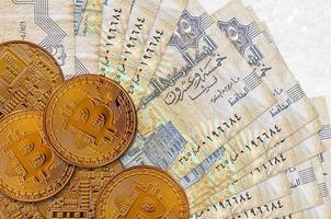 25 Egyptische piasters rekeningen en gouden bitcoins. cryptogeld investering concept. crypto mijnbouw of handel foto