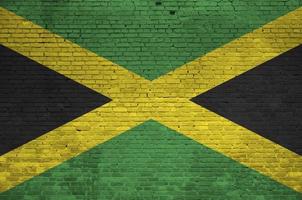 Jamaica vlag afgebeeld in verf kleuren Aan oud steen muur. getextureerde banier Aan groot steen muur metselwerk achtergrond foto