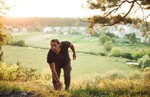 veroveren dat heuvel. landelijk tafereel. knap Mens met gespierd lichaam type is in de Woud Bij dag foto