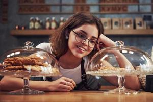 heerlijk koekjes. jong vrouw cafe arbeider binnenshuis. opvatting van bedrijf en onderhoud foto