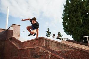 bovenstaand de obstakel. jong sport- Mens aan het doen parkour in de stad Bij zonnig dag foto