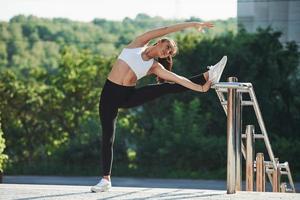 sportief vrouw aan het doen geschiktheid opdrachten in de stad Bij dag. in de buurt de leuningen foto