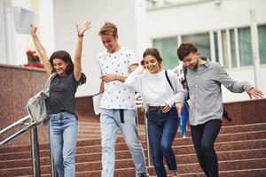 hebben mooi hoor humeur en mooi zo gesprek. groep van jong studenten in gewoontjes kleren in de buurt Universiteit Bij dag foto