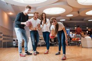 maak een mooi schot. jonge vrolijke vrienden hebben plezier in de bowlingclub in hun weekenden foto