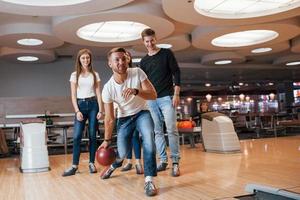 hier gaan we. jonge vrolijke vrienden hebben plezier in de bowlingclub in hun weekenden foto