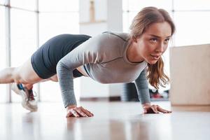 push-ups doen. sportieve jonge vrouw heeft 's ochtends een fitnessdag in de sportschool foto