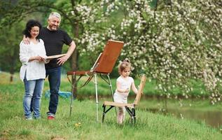 gelukkige ouders. oma en opa hebben plezier buiten met kleindochter. schilderij conceptie foto