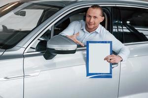 opvatting van zaken. manager zit in moderne witte auto met papier en documenten in handen foto