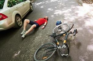 luchtfoto. slachtoffer op het asfalt. fiets- en zilverkleurig auto-ongeluk op de weg bij bos overdag foto