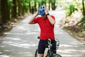 laten we gaan. fietser op een fiets is op de asfaltweg in het bos op zonnige dag foto