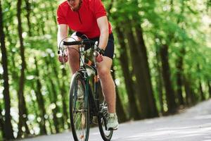 moderne sporten. fietser op een fiets is op de asfaltweg in het bos op zonnige dag foto