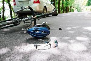 opvatting van onzorgvuldigheid. fiets- en zilverkleurig auto-ongeluk op de weg bij bos overdag foto