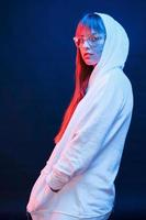 in moderne witte kleding. studio-opname in donkere studio met neonlicht. portret van een jong meisje foto