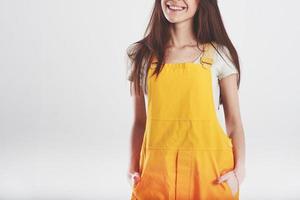 glimlachen voor de camera. brunette vrouw in geel uniform staat tegen wit achtergrond in de studio foto