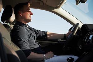 met ogen Gesloten. tevredenheid. bestuurder voelt mooi zo in zijn merk nieuw auto. rijden Bij zonnig dag foto