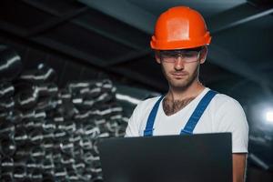 houdt laptop. Mens in uniform werken Aan de productie. industrieel modern technologie foto