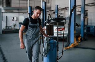 succesvol functie. mannetje monteur gebruik speciaal apparaat naar reparatie gebroken auto- in garage foto