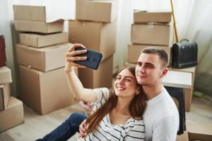 maken een selfie. vrolijk jong paar in hun nieuw appartement. opvatting van in beweging foto