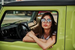 mooi vrouw in de groen modern auto poseren voor de camera foto