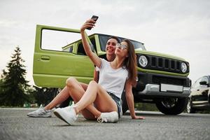twee vrouw vrienden hebben pret door zittend netjes de nieuw gren voertuig foto