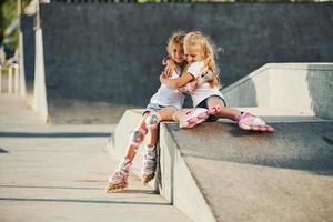 Aan de oprit voor extreem sport. twee weinig meisjes met rol skates buitenshuis hebben pret foto