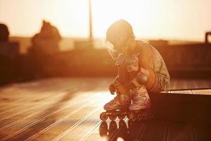 gelukkig schattig kind met haar rol schaatsen. ongelooflijk zonlicht foto