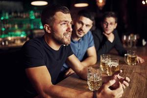 drie mannetje vrienden in de bar. ondersteunen verdrietig vriend. eenheid van mensen. met bier Aan de tafel foto