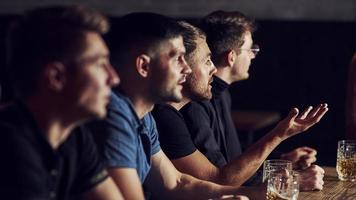 drie sport- fans in een bar aan het kijken voetbal. met bier in handen foto