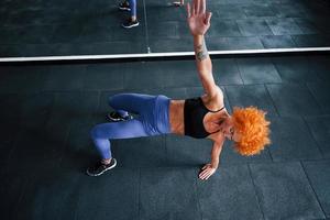 top visie. sportief roodharige meisje hebben geschiktheid dag in Sportschool Bij dag. gespierd lichaam type foto