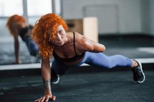 sterkte en flexibiliteit. sportief roodharige meisje hebben geschiktheid dag in Sportschool Bij dag. gespierd lichaam type foto