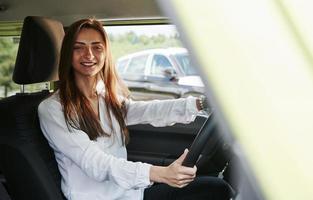 vrolijk vrouw bestuurder is in haar nieuw auto. interieur van modern auto- foto