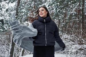 afbeelding in beweging. portret van charmant vrouw in de zwart jasje en grijs sjaal in de winter Woud foto