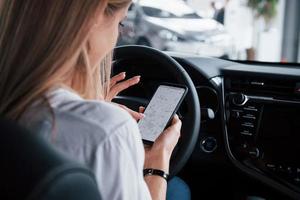 sporen de route. mooi blond meisje zittend in de nieuw auto met modern zwart interieur foto