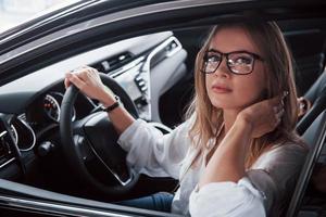 mode bedrijf vrouw. mooi blond meisje zittend in de nieuw auto met modern zwart interieur foto