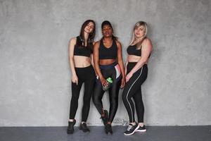 sportief aan het eten. groep van multi etnisch Dames staand in de studio tegen grijs achtergrond foto