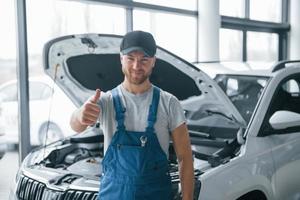 wij zullen worden altijd gelukkig naar zien u opnieuw. werknemer in de blauw gekleurde uniform staat in de auto- salon foto