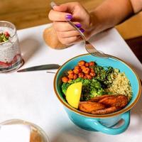 vrouw die smakelijke kipsalade met dessert eet foto